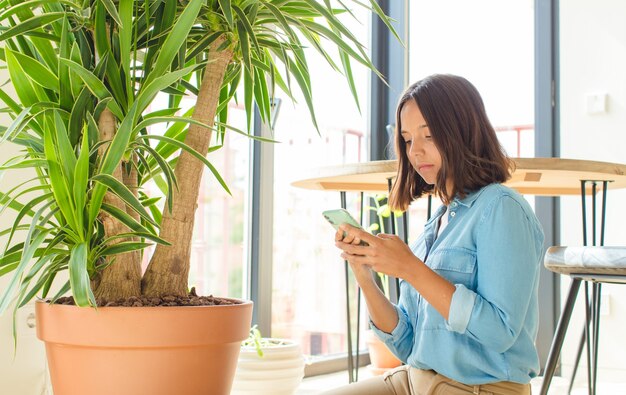 Young pretty woman using her phone at home