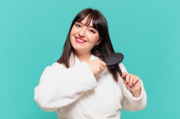 Young pretty woman wearing bathrobe happy expression and holding a hair brush