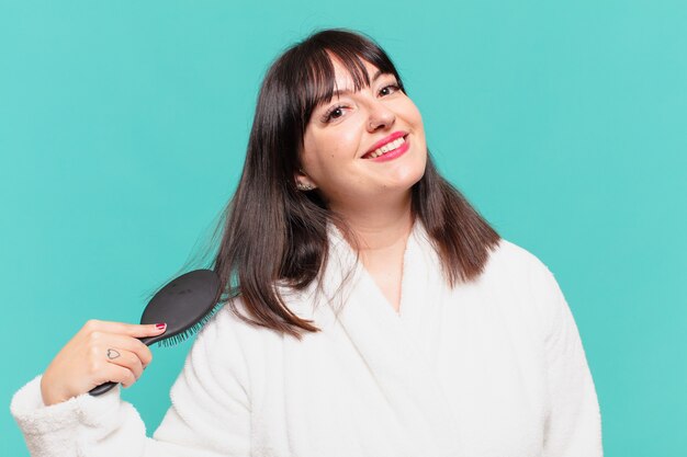 Young pretty woman wearing bathrobe happy expression and holding a hair brush