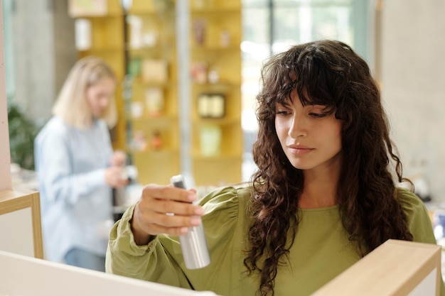 Young pretty woman with dark long wavy hair choosing haircare product