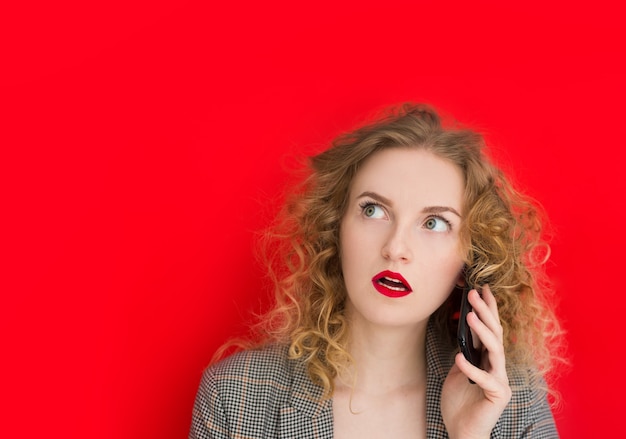 Young pretty woman with phone shocked against red wall, web banner