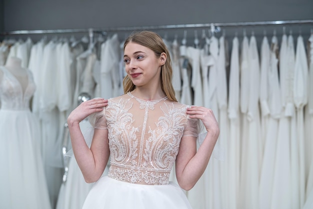 Young prety woman is trying white wedding dresses