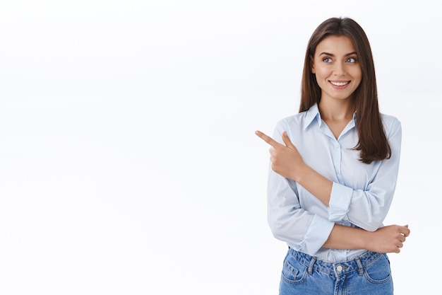 Young professional and confident lady boss searching how improve her company visit business lectures pointing finger left and look curious with happy pleased smile, stand white wall