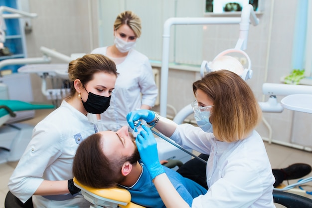 Young professional doctor dentist in a modern office with dental equipment. The concept of health insurance and free dental care. Prosthetics and installation of veneers.