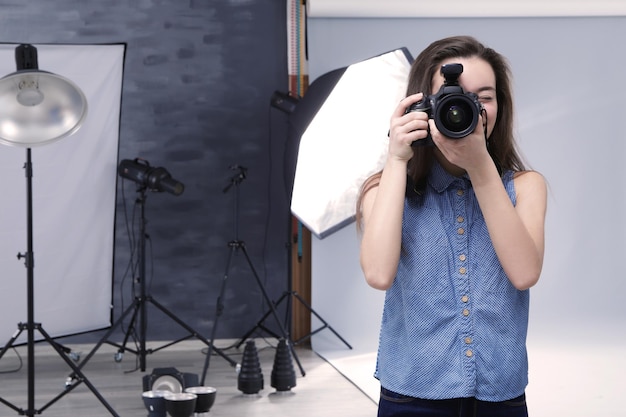 Young professional photographer with camera in studio