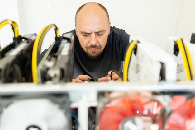 Young programmer adjusting cryptocurrency mining rig to optimal operational settings high quality photo