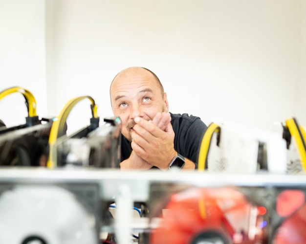 Young programmer adjusting cryptocurrency mining rig to optimal operational settings. High quality photo