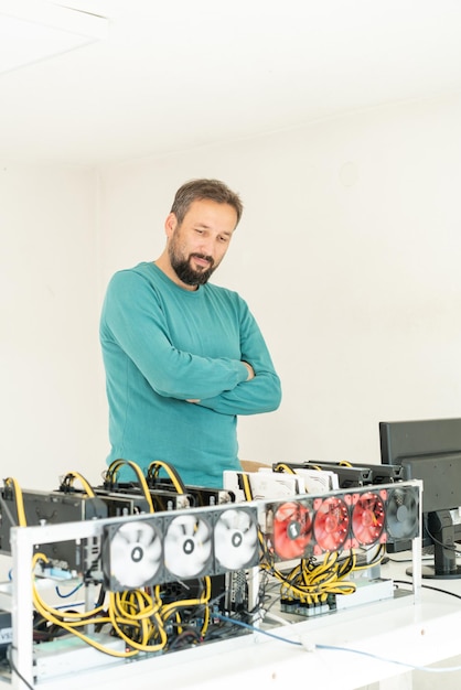 Young programmer adjusting cryptocurrency mining rig to optimal operational settings. High quality photo