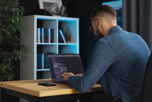 Young programmer man coding on laptop