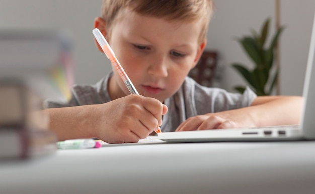 Young pupil making his homework at the desk in home