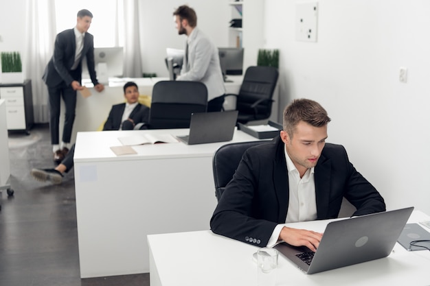 A young purchasing Manager in a black suit makes a large online order via an intranet in a laptop for his company.