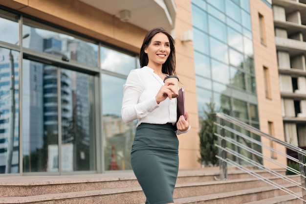 Young purposeful professional business woman wearing a blouse and a skirt leaving the business center