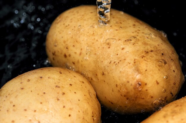 Photo young raw potatoes in their skins are washed in clean water before cooking close-up macro photography