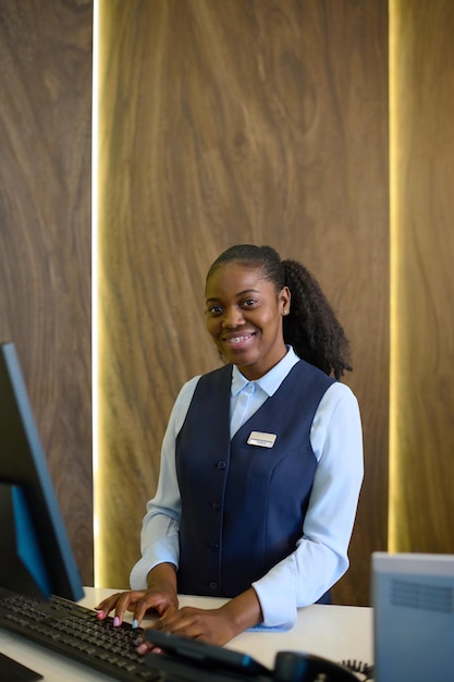 Young receptionist entering personal data of guests into database by counter