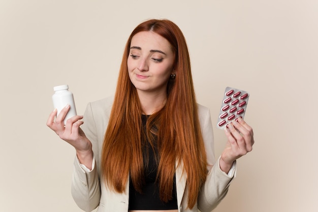 Young red hair business woman holding pills isolated