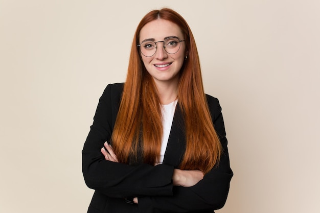 Young red hair business woman smiling on a beige background