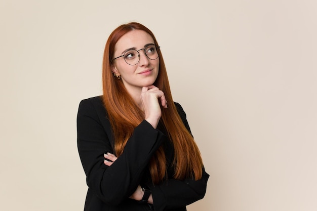 Young red hair business woman smiling on a beige background