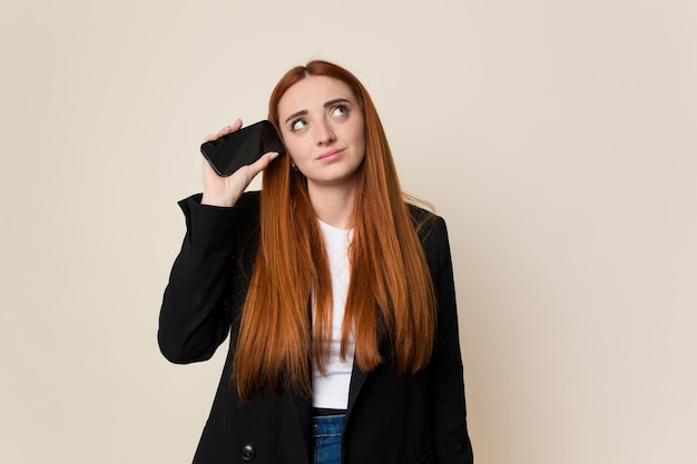 Young red hair business woman using her mobile phone isolated