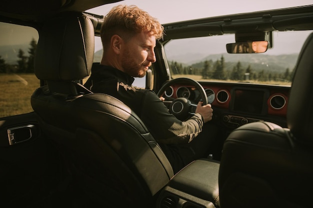 Young red hair man driving terrain vehicle on a roadtrip in nature