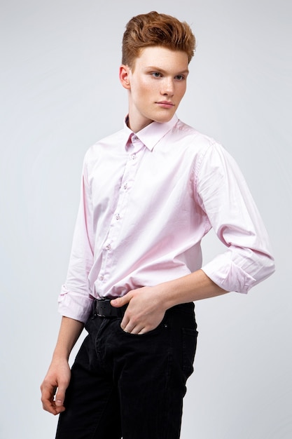 Young red-haired man dressed in a pink shirt and trousers