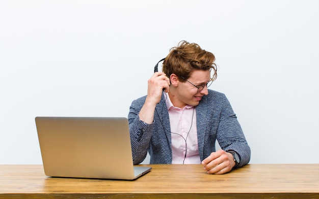 Young red head businessman working in his desk with headphones