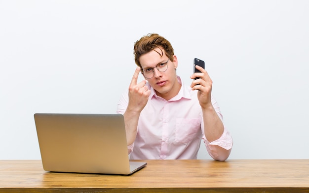 Young red head businessman working in his desk with a monile phone