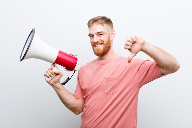 Young red head man with a megaphone against white background