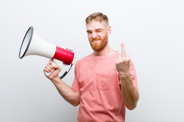 Young red head man with a megaphone against white 