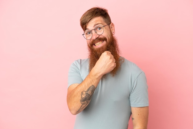 Young reddish caucasian man isolated on pink background celebrating a victory