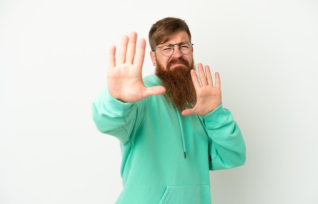 Young reddish caucasian man isolated on white background nervous stretching hands to the front