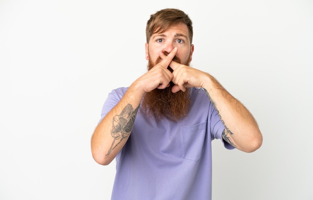 Young reddish caucasian man isolated on white background showing a sign of silence gesture