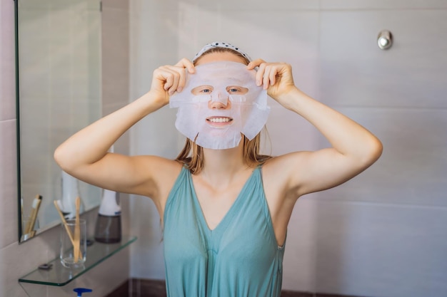 Young redhaired woman doing facial mask sheet Beauty and Skin Care Concept