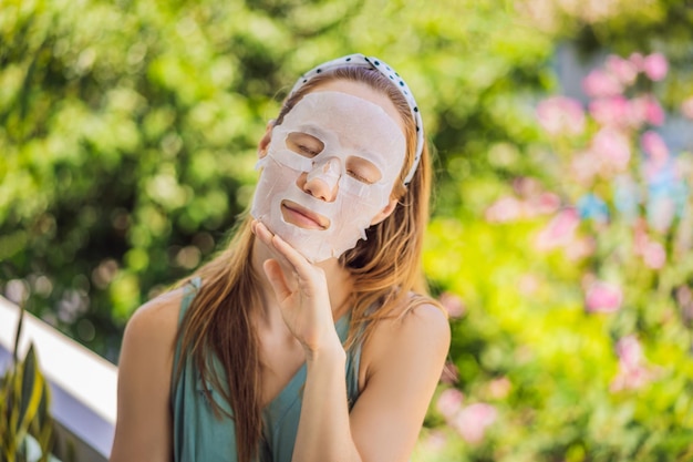 Young redhaired woman doing facial mask sheet beauty and skin care concept