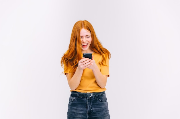 young redhead girl in casual clothes using a smartphone happy win