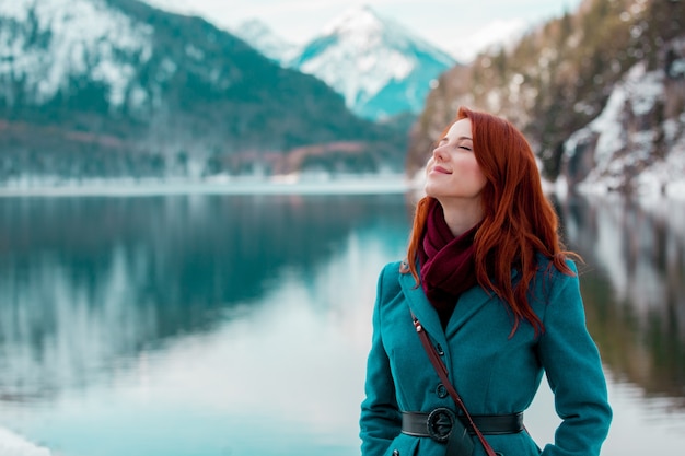 Young redhead girl in coat near lake in Alps, Germany