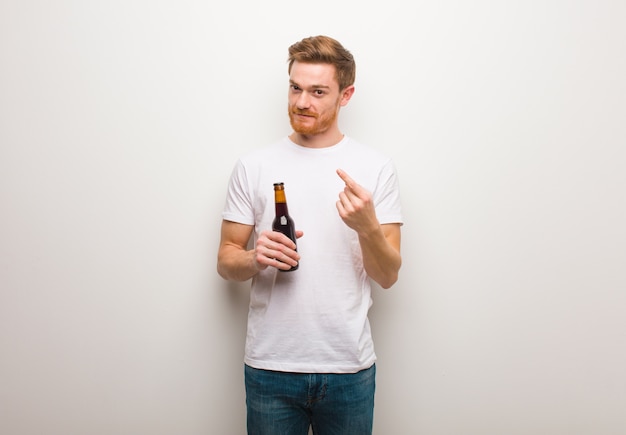 Young redhead man. Holding a beer.