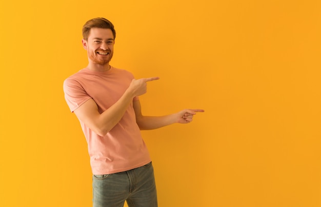 Young redhead man pointing to the side with finger