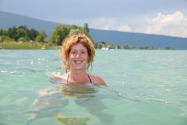 Young redhead and natural bathing in a lake