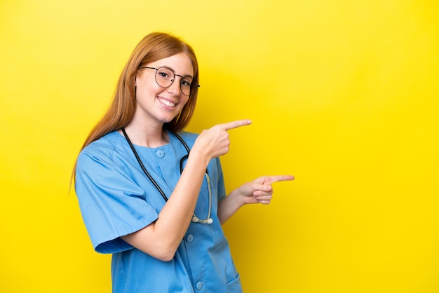 Young redhead nurse woman isolated on yellow background pointing finger to the side and presenting a product