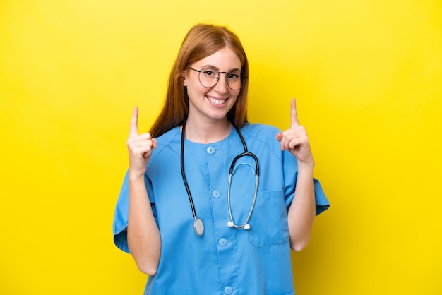 Young redhead nurse woman isolated on yellow background pointing up a great idea