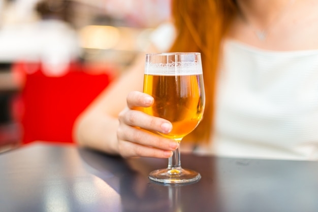 Young redhead pretty girl enjoying a beer at a mall