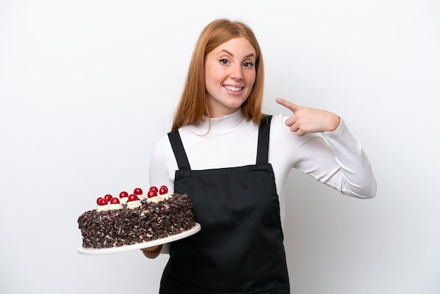 Young redhead woman holding birthday cake isolated on white background giving a thumbs up gesture