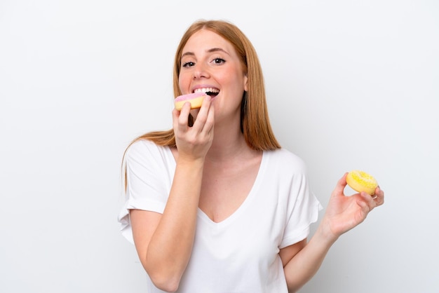 Young redhead woman isolated on white background eating a donut