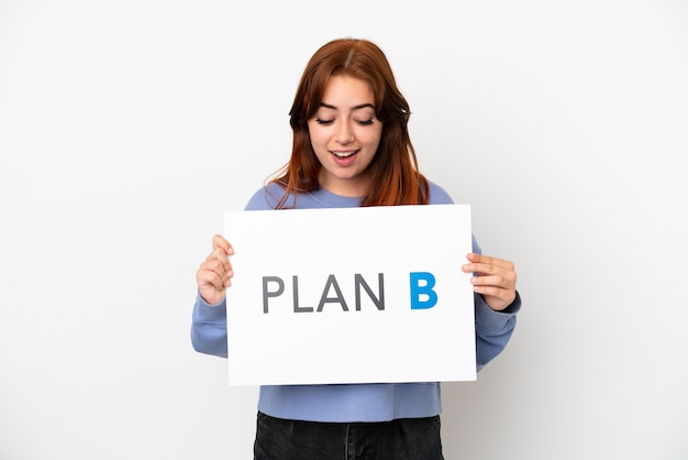 Young redhead woman isolated on white background holding a placard with the message PLAN B