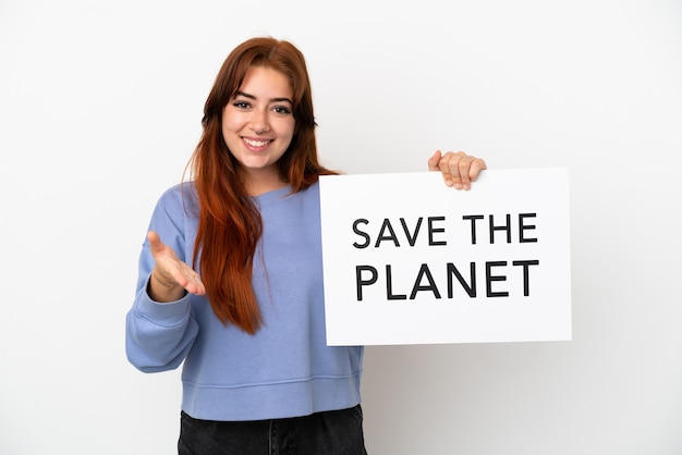 Young redhead woman isolated on white background holding a placard with text Save the Planet making a deal