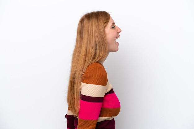 Young redhead woman isolated on white background laughing in lateral position