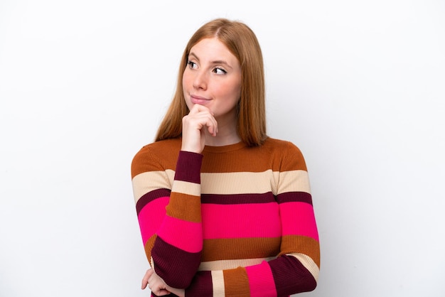 Young redhead woman isolated on white background and looking up