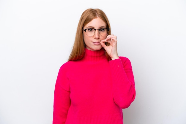 Young redhead woman isolated on white background showing a sign of silence gesture