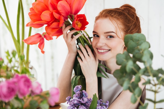 Young redhead woman looking up and holding red tulips