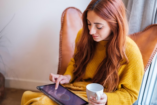 Young redhead woman managing the different technologies of the house from the home app Concept future technology home